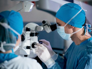 Surgeons performing an eye surgery under the microscope